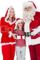 Santa and Mrs Claus smiling at camera with little girl