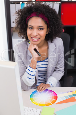 Smiling female photo editor at office desk