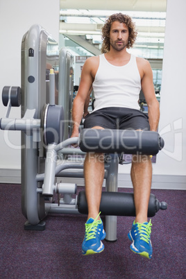 Portrait of handsome man doing leg workout at gym