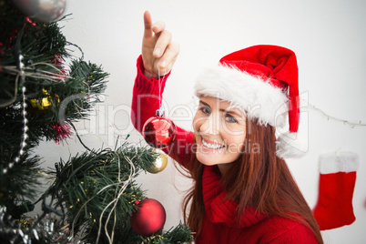 Festive redhead hanging bauble on tree