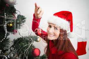 Festive redhead hanging bauble on tree