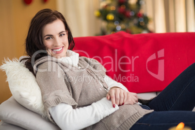 Happy brunette relaxing on the couch at christmas
