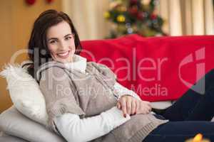 Happy brunette relaxing on the couch at christmas
