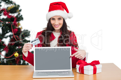 Festive brunette shopping online with laptop and pointing screen