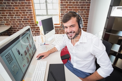 Smiling photo editor using computer in office