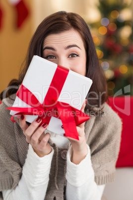 Brunette showing gift on the couch at christmas