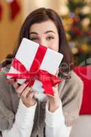 Brunette showing gift on the couch at christmas