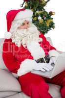 Father christmas using laptop on the sofa