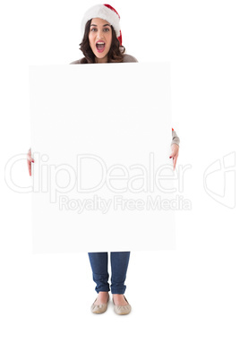 Happy brunette in santa hat showing white poster