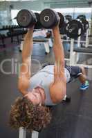 Young man exercising with dumbbells in gym