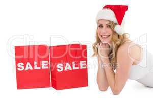Festive blonde lying with sale shopping bags