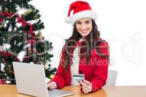 Festive brunette shopping online with laptop