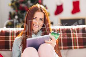 Festive redhead shopping online with tablet