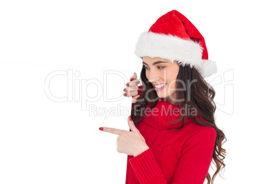 Beauty brunette in santa hat pointing white poster