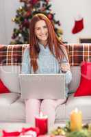 Festive redhead shopping online on couch