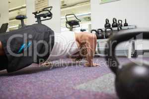 Side view of man doing push ups in gym