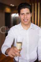 Handsome man smiling at camera holding champagne