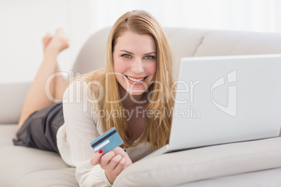 Blonde shopping online lying on the couch Blonde shopping online lying on the couch