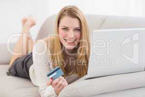 Blonde shopping online lying on the couch