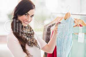 Smiling shopping brunette looking at blue dress
