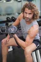 Young man exercising with dumbbell in gym