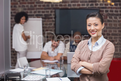 Smiling young businesswoman with colleagues in background