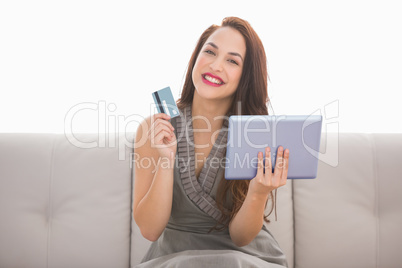 Smiling brunette holding credit card an tablet