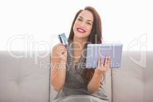 Smiling brunette holding credit card an tablet