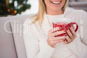 Blonde having hot chocolate on the couch at christmas