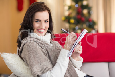 Brunette lying on the couch writing her christmas list