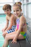 Cute little siblings sitting poolside