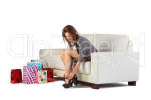 Cute woman sitting on couch taking off her shoes