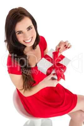 Smiling brunette sitting and opening gift