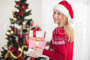 Blonde holding pile of gifts in front of the christmas tree