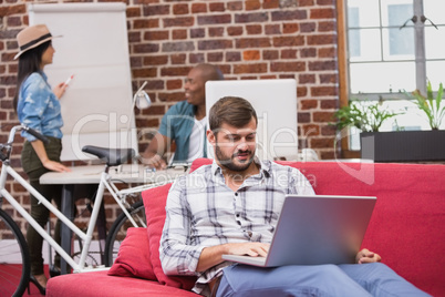 Man using laptop on couch in office