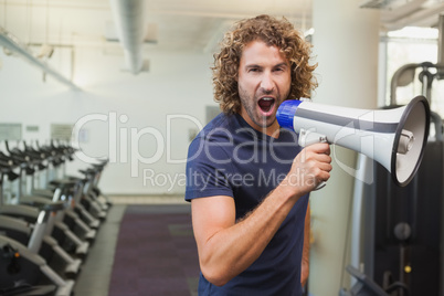 Portrait of trainer shouting into bullhorn in gym