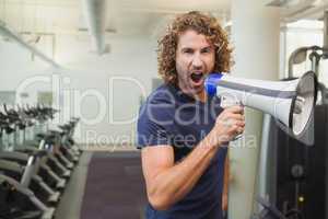 Portrait of trainer shouting into bullhorn in gym