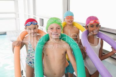 Cute little kids standing poolside with foam rollers