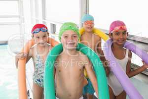 Cute little kids standing poolside with foam rollers