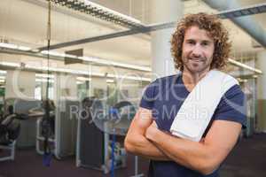 Smiling handsome trainer with arms crossed in gym