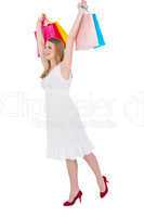 Excited blonde holding up shopping bags in white dress