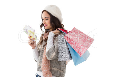 Happy brunette holding cash and shopping bags