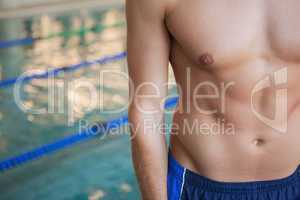 Mid section of a shirtless fit swimmer by pool