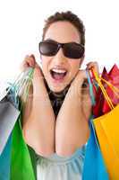 Portrait of excited brunette with sunglasses holding shopping ba