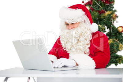 Father christmas using his laptop near christmas tree