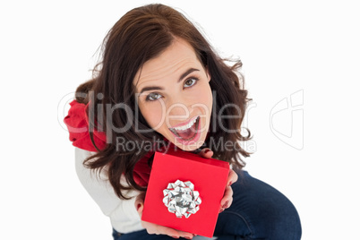 Excited brunette sitting holding red gift