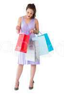 Stylish brunette in purpul dress opening shopping bag