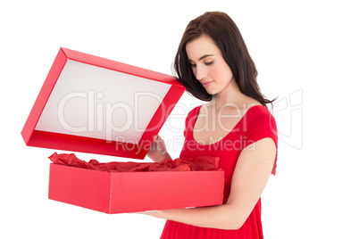 Stylish brunette in red dress opening gift