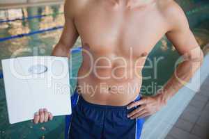 Mid section of a shirtless fit swimmer with weighing scales by p