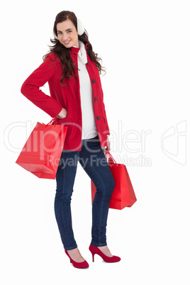 Cheerful brunette in winter clothes posing and holding shopping